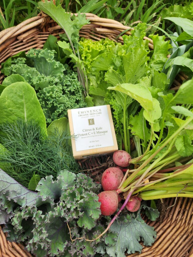  Fresh garden greens and kale in a wicker basket with Eminence organic skincare natural ingredients